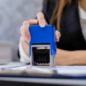 personne tamponant un document avec un tampon encreur